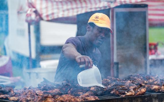 2017 Caribbean food vendor seasoning chicken on stall at Moor Park.