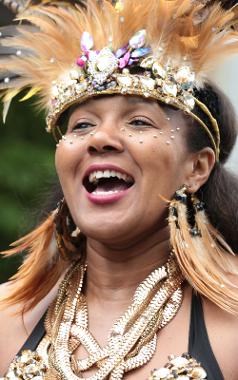 Smiling woman wearing gold headdress with jewels on, during 2017 parade.