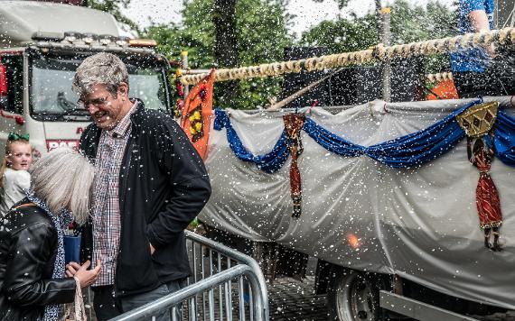 Man and woman being sprayed by foam from a float in the Caribbean Carnival 2017 parade.