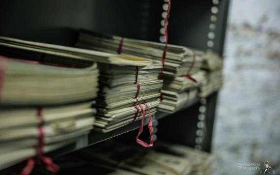 Old documents stacked up on shelves, tied in red string, in Harris storage.