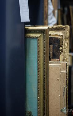 Paintings in their frames, stored on shelves in Harris storage area.