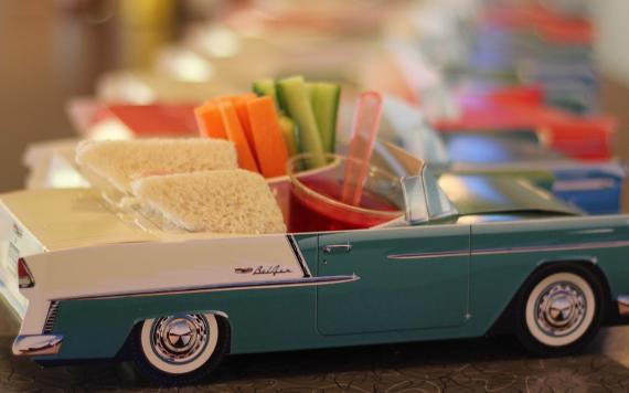 A kids food option of sandwich triangles and vegetable sticks in a novelty Cadillac plate