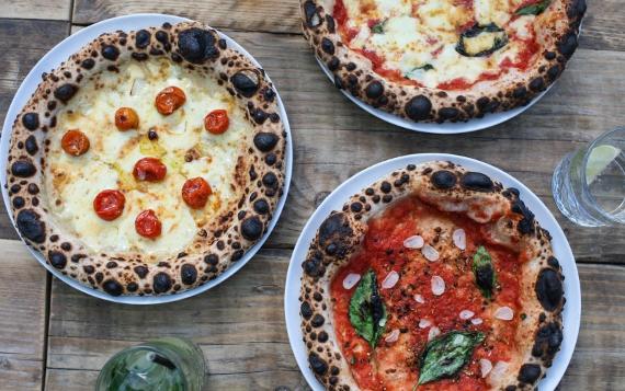 Three pizzas and drinks on a table from Lost Bar and Pizzeria