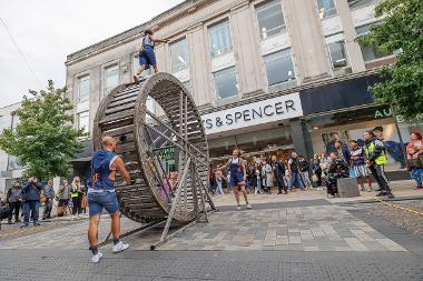 Performer walking along giant wheel