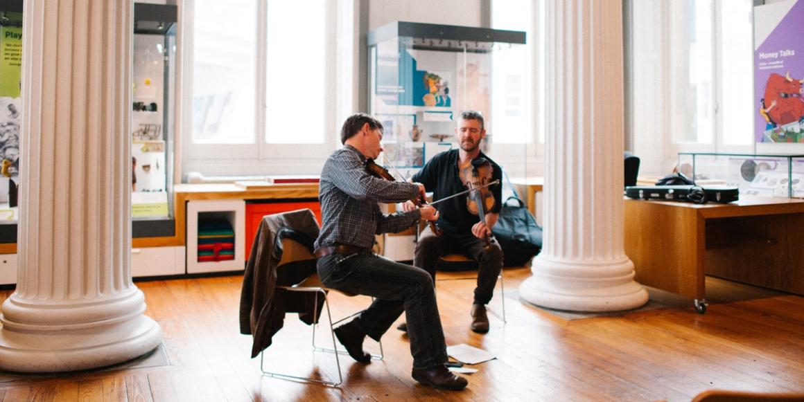 Banner: violinists performing at The Harris