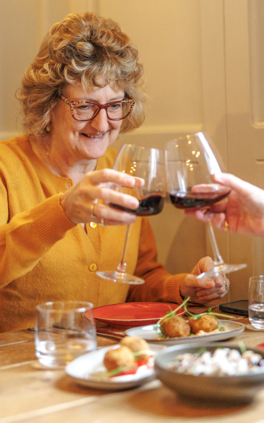 People raising glasses of wine over a meal