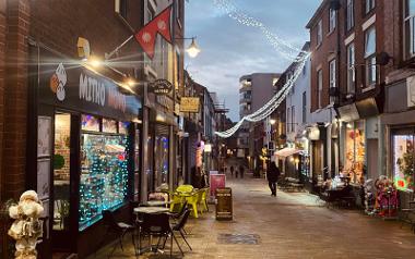 Outside Mitho Momo with Christmas light decorations looking down Cannon Street in the evening