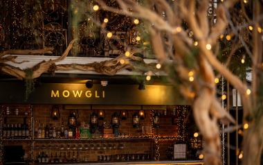 A view of the bar inside Mowgli with ornate tree branches, oil lanterns and warm lighting