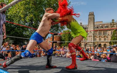 Two brightly dressed wrestlers fighting in a wrestling ring on the Flag Market