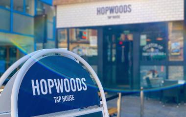 A sign outside Hopwoods Tap House next to their outdoor seating area