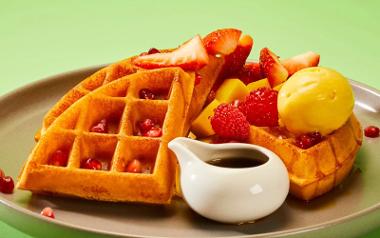 Strawberries, raspberries, mango, pomegranate, maple syrup and mango sorbet on top of Heavenly Desserts American waffles.