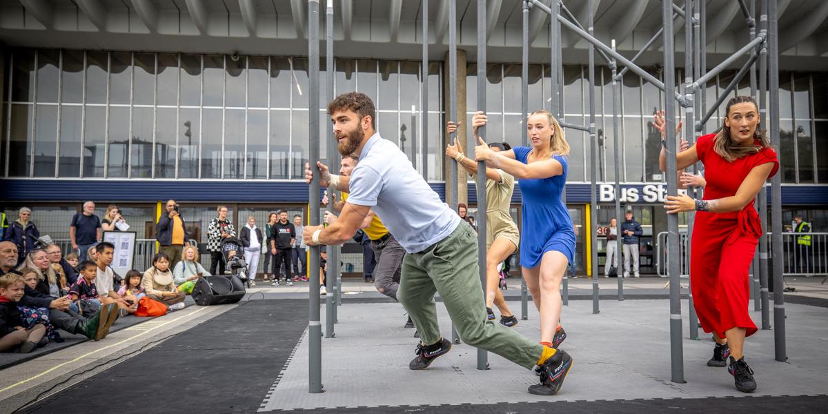 A group of performers dancing around scaffolding in-front of Preston Bus Station