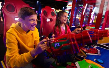 Two kids playing a Nerf shooting arcade game inside Hollywood Bowl Preston