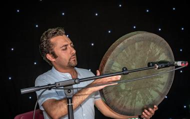 Man on stage playing large disc shaped instrument. Photo by Michael Porter.