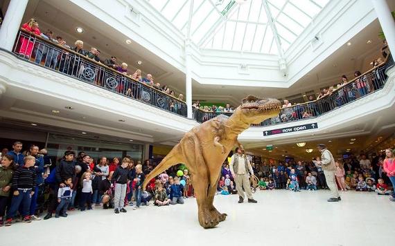 Dinosaur performance being watched by crowd in St George's Shopping Centre.