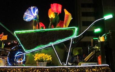 Lit up float showing wheelbarrow and flowers during Preston torchlight procession.