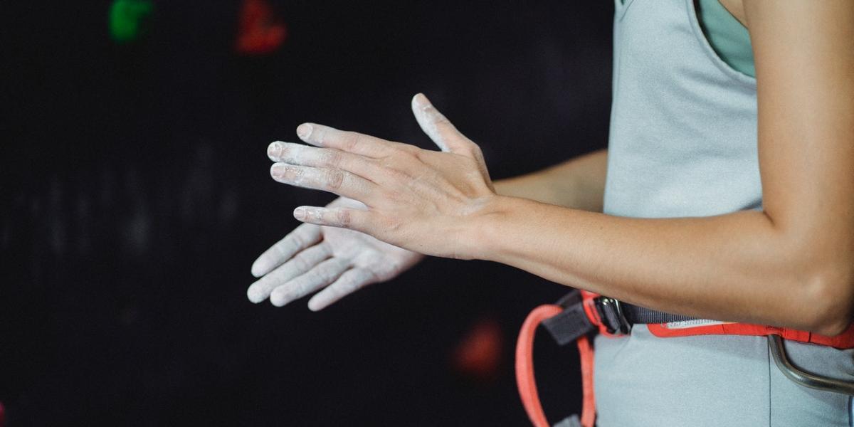 Climber dusting hands with chalk at indoor climbing wall.