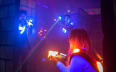 Two boys in blue light up gear face against two girls in orange gear in Laserforce Preston