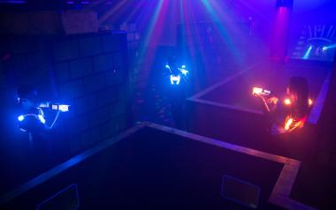 Three people face off in a battle with laser guns in an arena inside Laserforce Preston