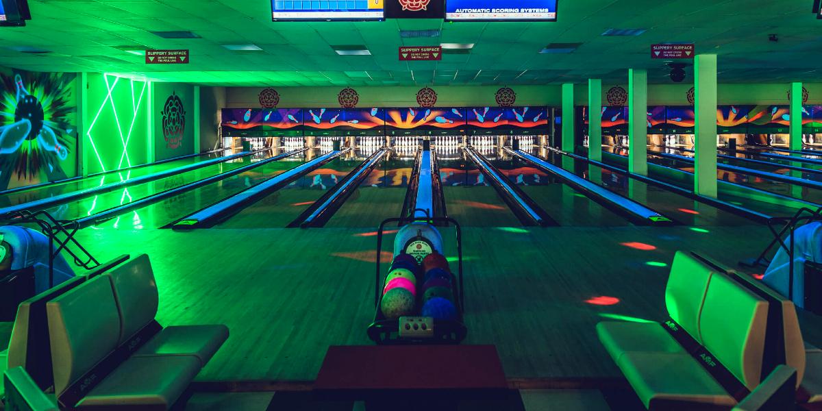 Bowling lanes at Red Rose Bowl lit up in green.