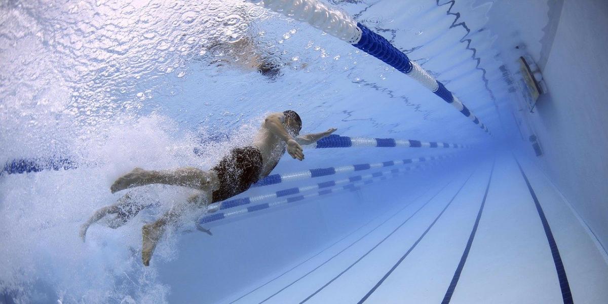 Underwater view of man swimming in indoor swimming pool.