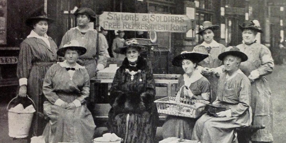 Old black and white showing women sat at the Sailors and Soldiers Free Buffet sign.