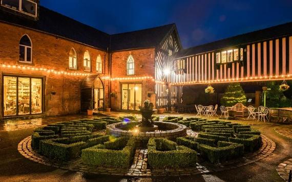 Fountain and shrubbery in Samlesbury Hall courtyard area at night, lit by fairy lights.