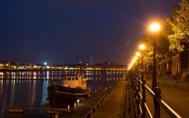 Boat in Preston Marina and view of dock and skyline at night.