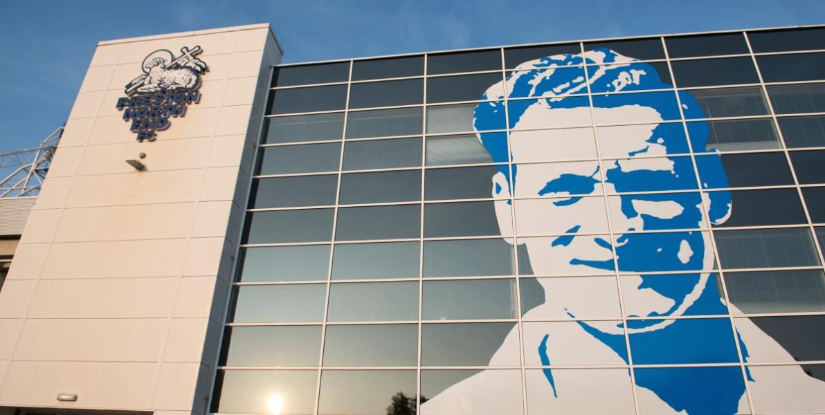 Large image of Sir Tom Finney's face and Preston North End FC logo on the side of Deepdale Stadium.