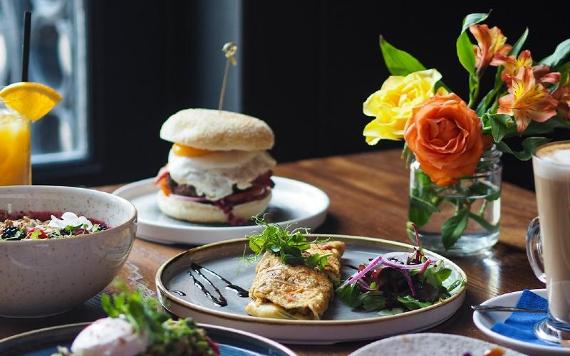 Assorted breakfast dishes on table with flowers inside 1842.