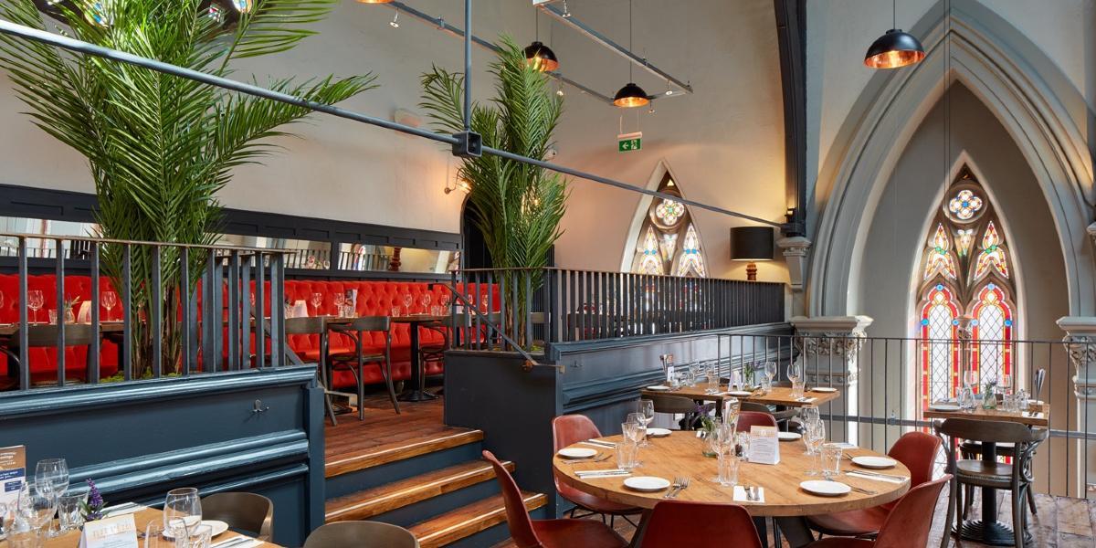 Red bench seating and dining tables in Preston's Bistrot Pierre upstairs dining area.