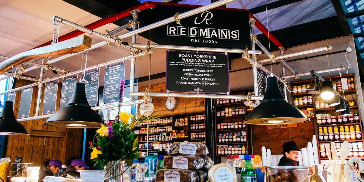 Redmans Fine Foods sign and view of food and preserves over the counter.