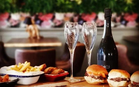 Burgers and fries with bottle of Prosecco inside Baluga Bar.