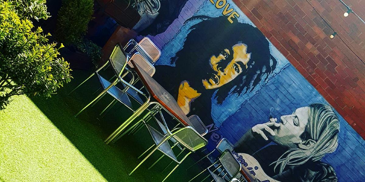 Hartleys Wine Bar beer garden with Kurt Cobain and Bob Marley artwork on walls.