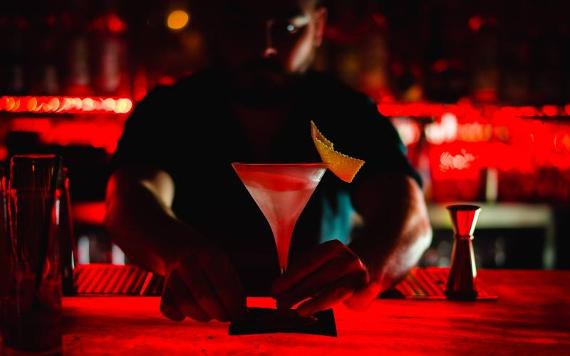 Kuckoo bartender placing cocktail on bar counter.