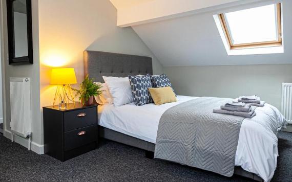 Modern grey and yellow double bedroom inside City Haven apartment.