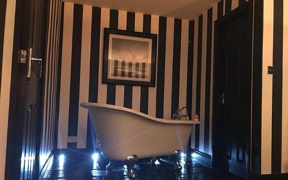 Free-standing bath, and black and white striped walls, in hotel room at No.10 Preston.