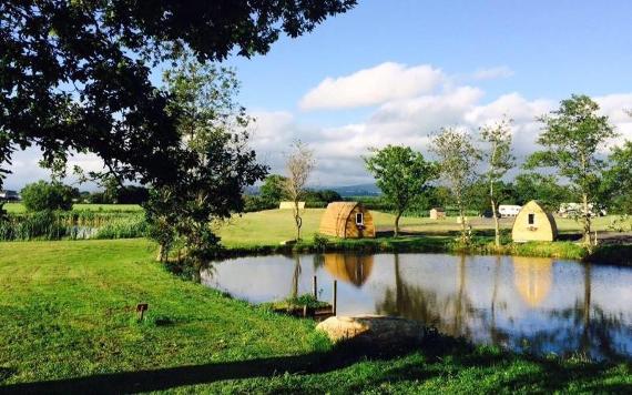 Camping pods by water at Poplar Grove Farm Caravan Park.