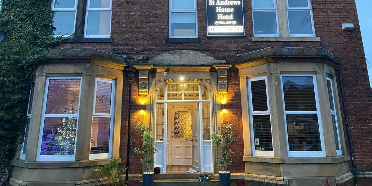 Front exterior of St Andrews House Hotel, lit up at night.