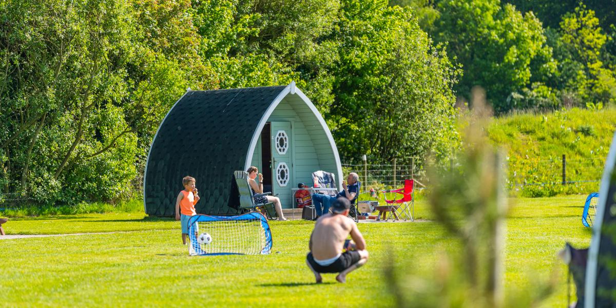 Families playing and relaxing outside their camping pods at Stanley Villa Farm