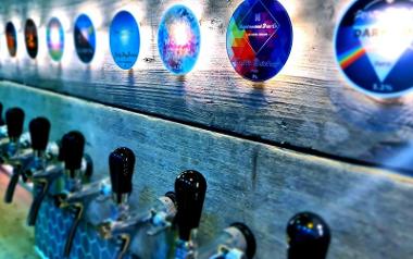 Array of craft beer logos on display above taps behind Florianas bar.