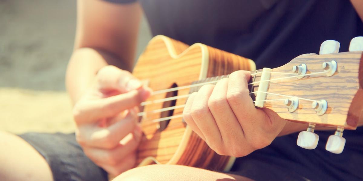 Man playing Ukulele in the sun.