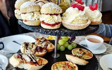 Cream cakes and savoury nibbles on a afternoon tea stand inside Bread and Butter.