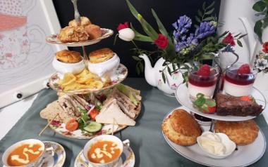 Two afternoon tea stands, one savoury and one sweet, on a table inside The Village Teapot café. 