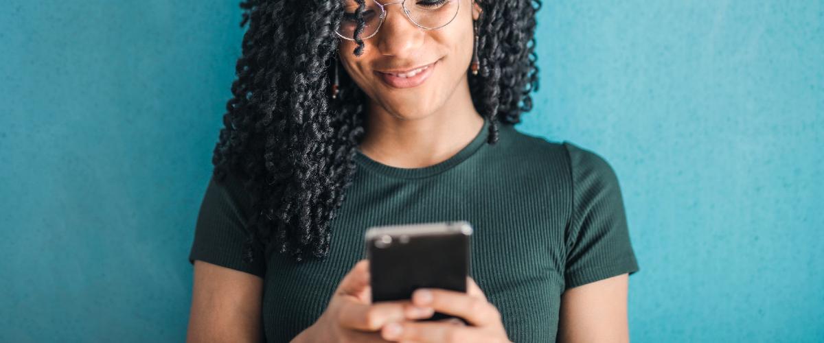 Woman smiling whilst using mobile phone.