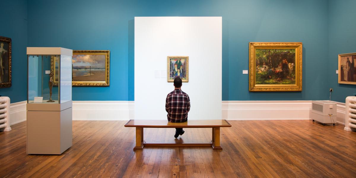 Man sat on bench admiring painting on wall inside Harris Gallery, Preston.