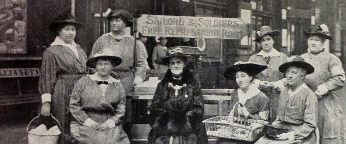 Vintage photo of women sat by Sailors and Soldiers Free Buffet sign in Preston Train Station.