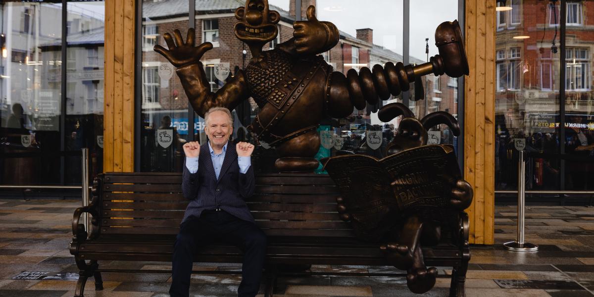 Nick Park sat on Wallace and Gromit bench at Preston Markets.