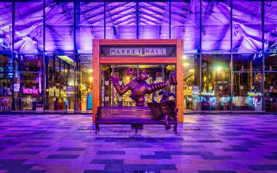 Wallace and Gromit statue at night, lit by Preston Market's purple lighting.